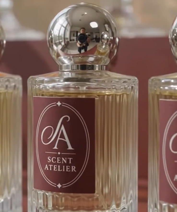 Izbliza: bočica parfema Scent Atelier od 30 ml sa srebrnim čepom i oxblood etiketom s monogramom.